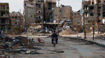 A man drives his motorbike past damaged buildings in Harasta, east of Damascus. (Photo: AFP) 