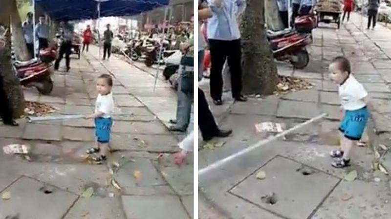 The toddler was trying to shoo away officials who wanted his grandmother to vacate as her makeshift shop was taking up too much sidewalk space. (Credit: YouTube)